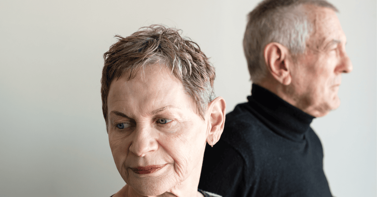 An older couple sitting back to back, not looking at each other, reflecting the emotional distance of a marriage in crisis in Israel